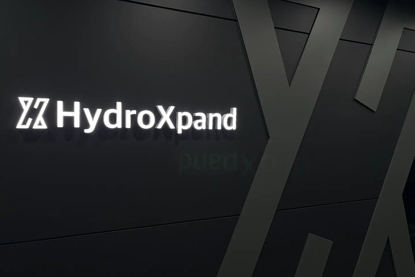 Illuminated HydroXpand logo on a dark wall